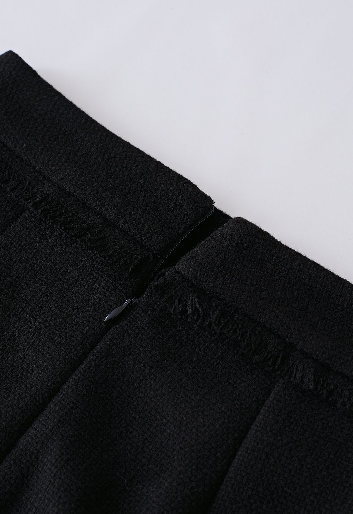 تنورة قصيرة من التويد مزينة بشراشيب باللون الأسود