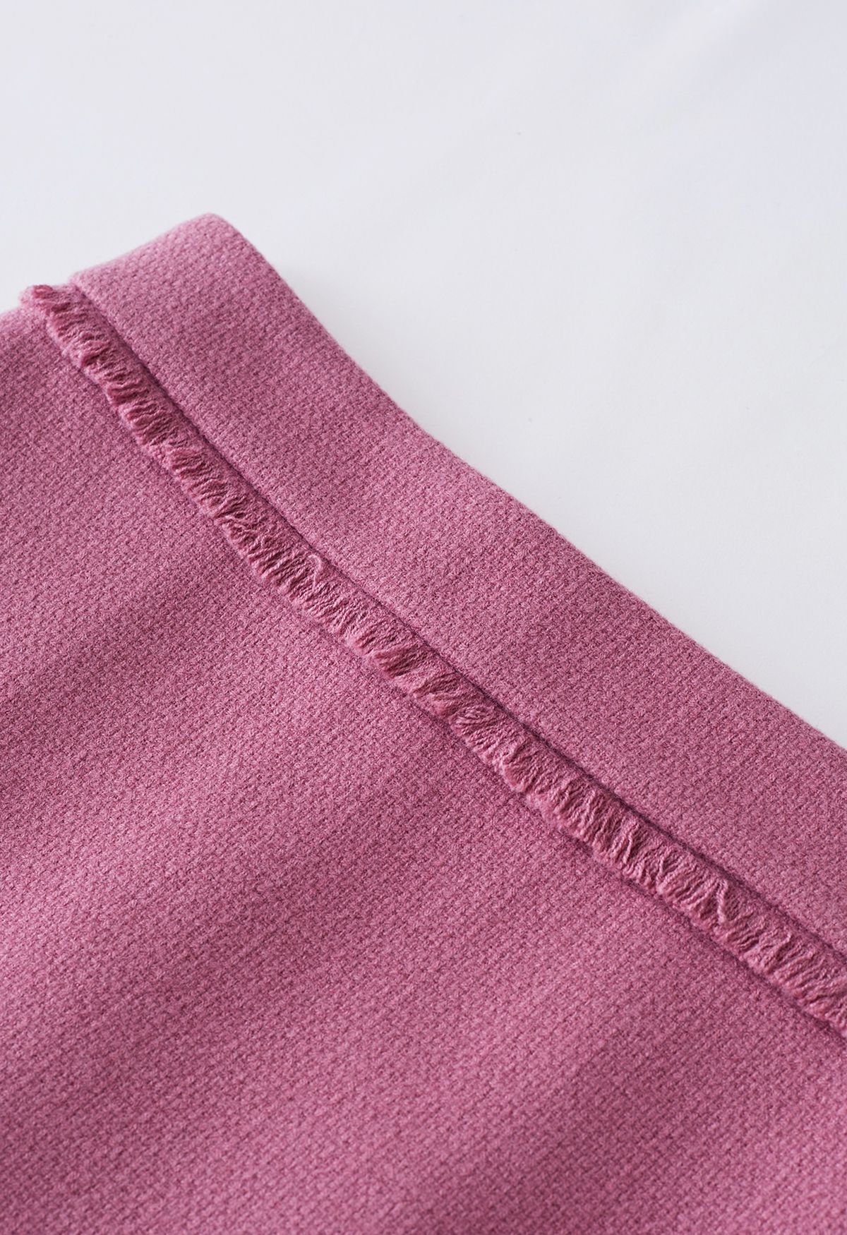 تنورة قصيرة مزينة بشراشيب من التويد باللون الوردي