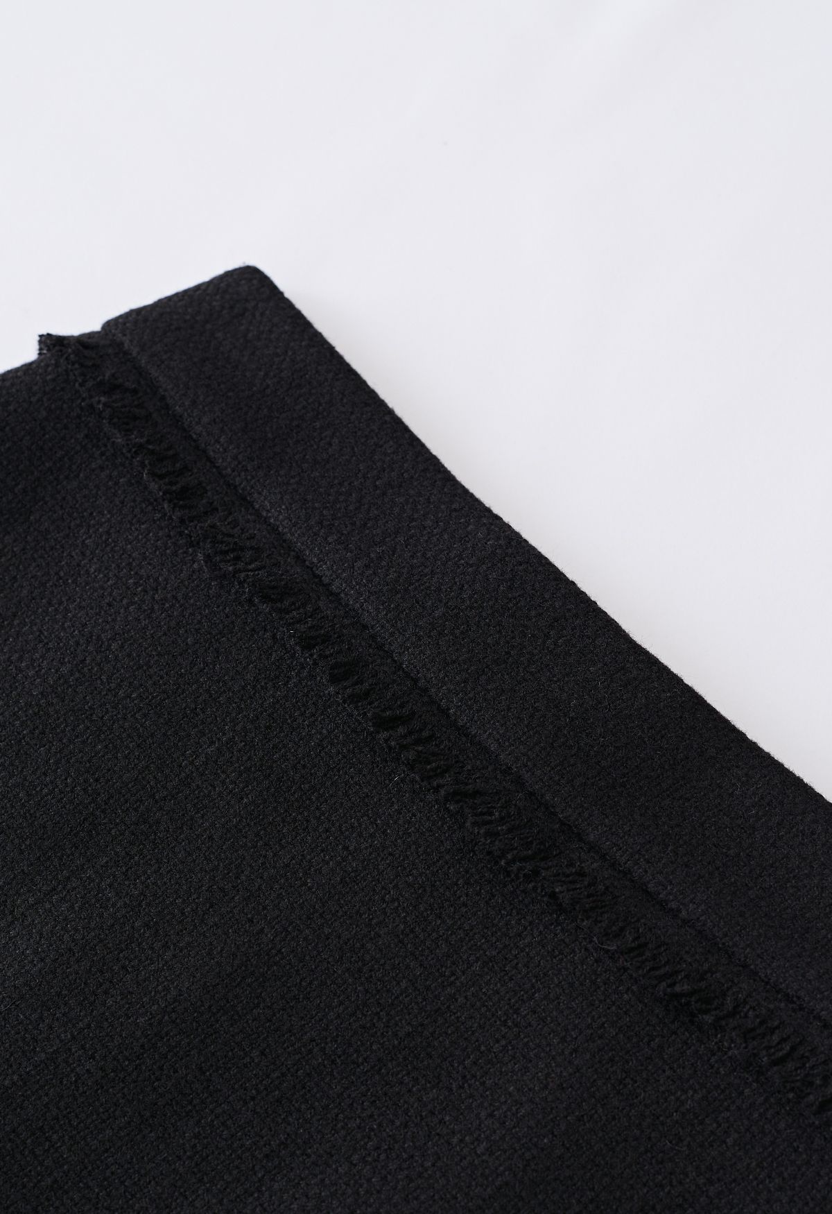 تنورة قصيرة من التويد مزينة بشراشيب باللون الأسود
