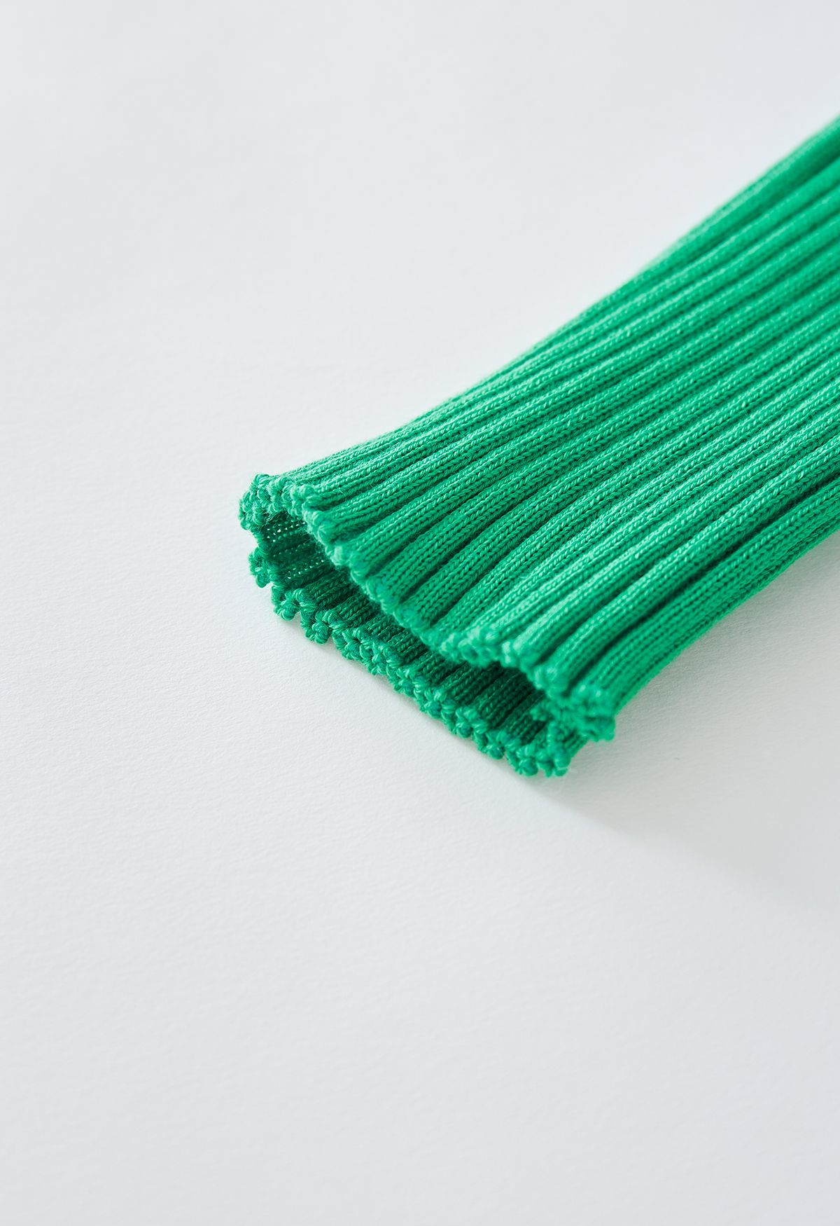 بلوزة محبوكة بياقة على شكل V وتنورة مطوية باللون الأخضر