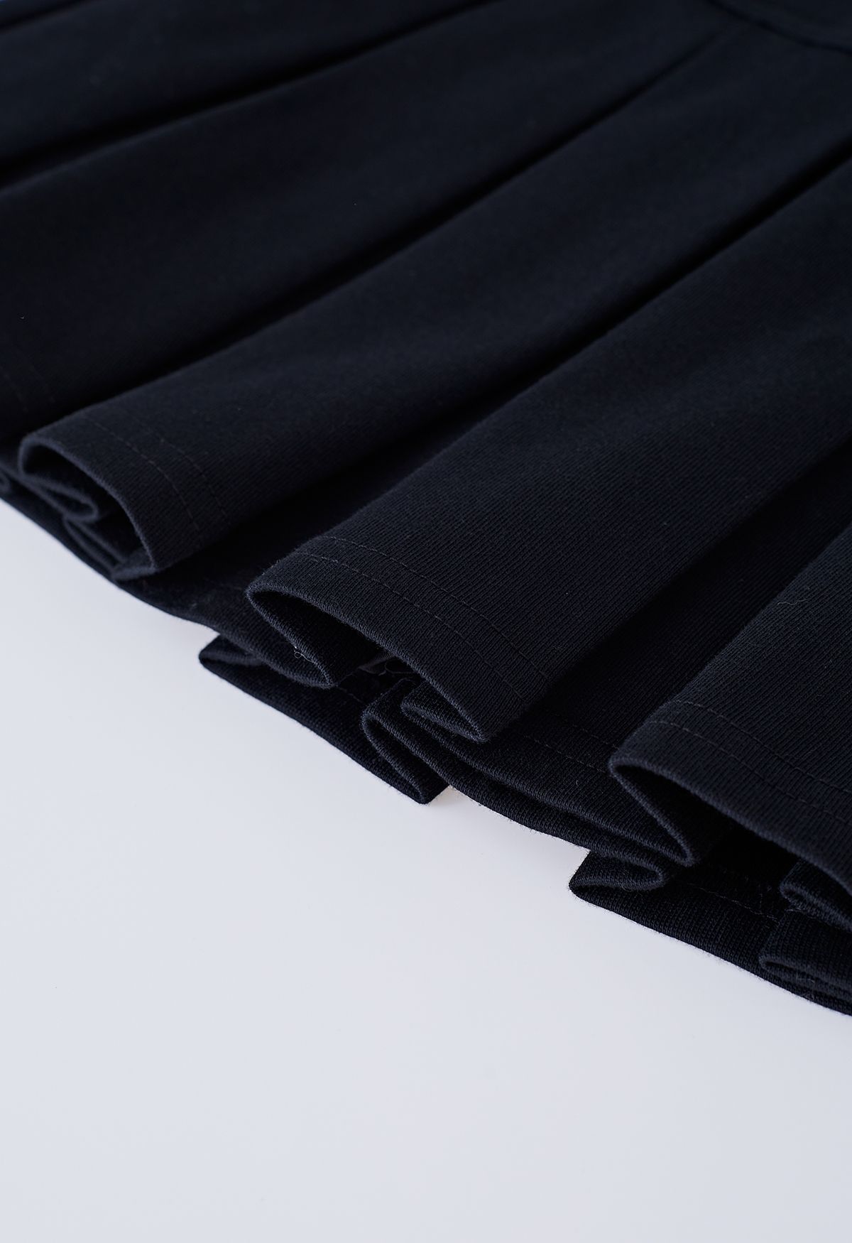تنورة ميني مضيئة بخصر مطاطي وطيات باللون الأسود