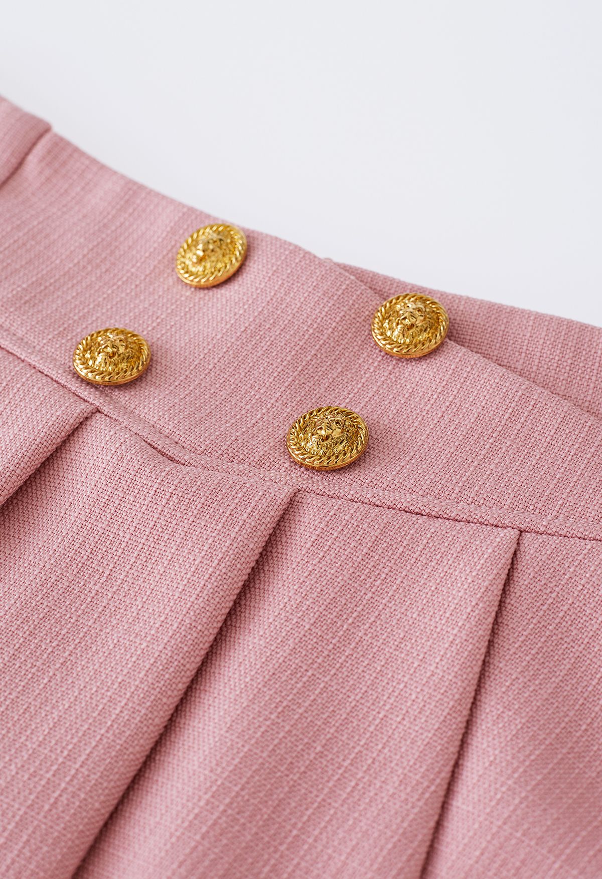تنورة قصيرة مطوية بأزرار ذهبية باللون الوردي