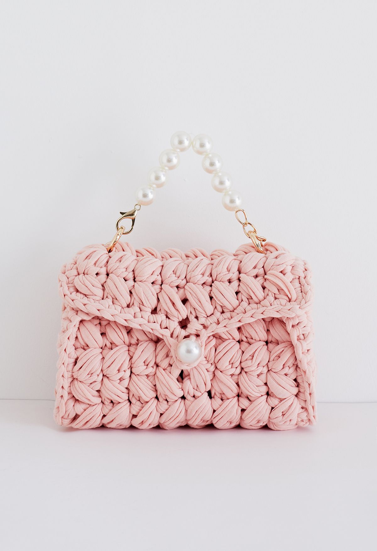 حقيبة صغيرة منسوجة مزينة بسلسلة من اللؤلؤ باللون الوردي