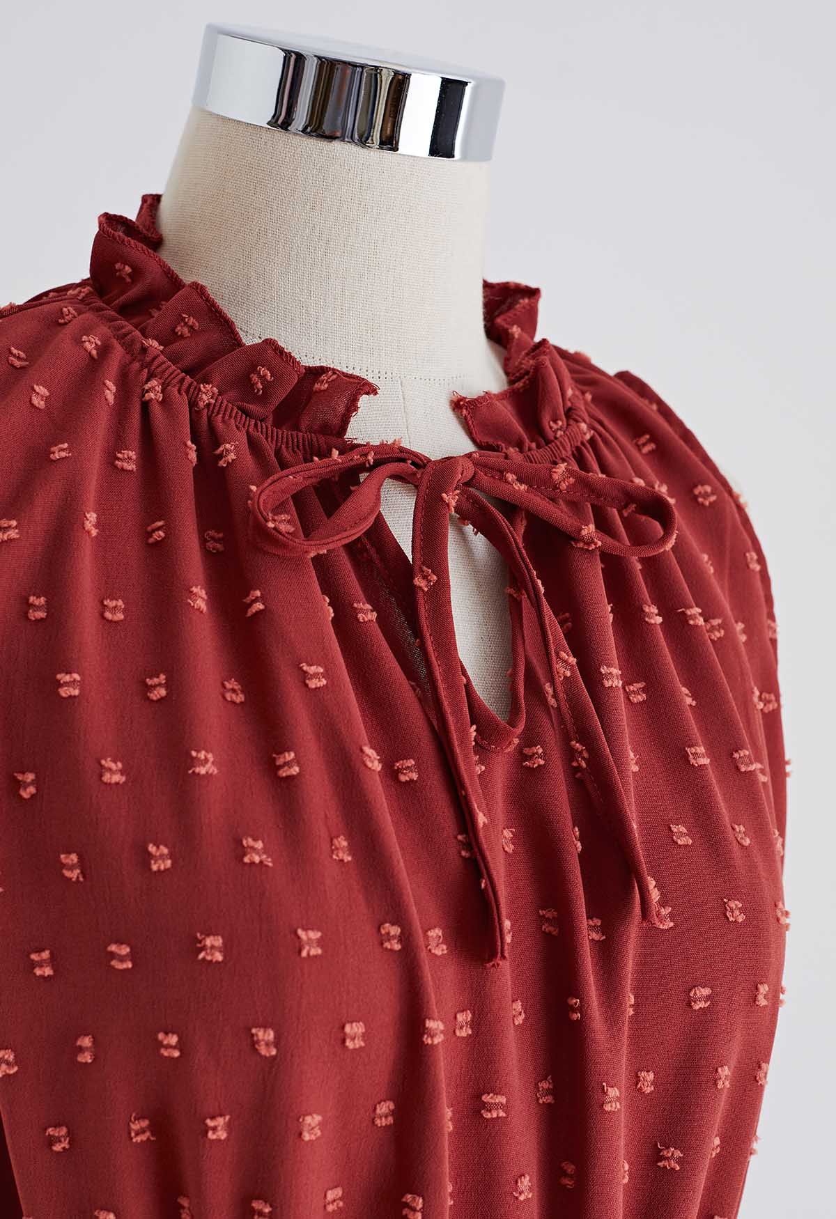 فستان بطيات منقّطة وربطة عنق باللون الأحمر الصدأ