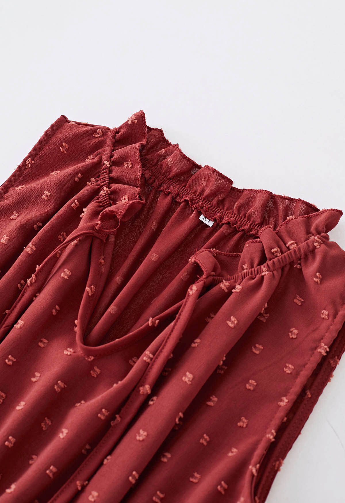 فستان بطيات منقّطة وربطة عنق باللون الأحمر الصدأ