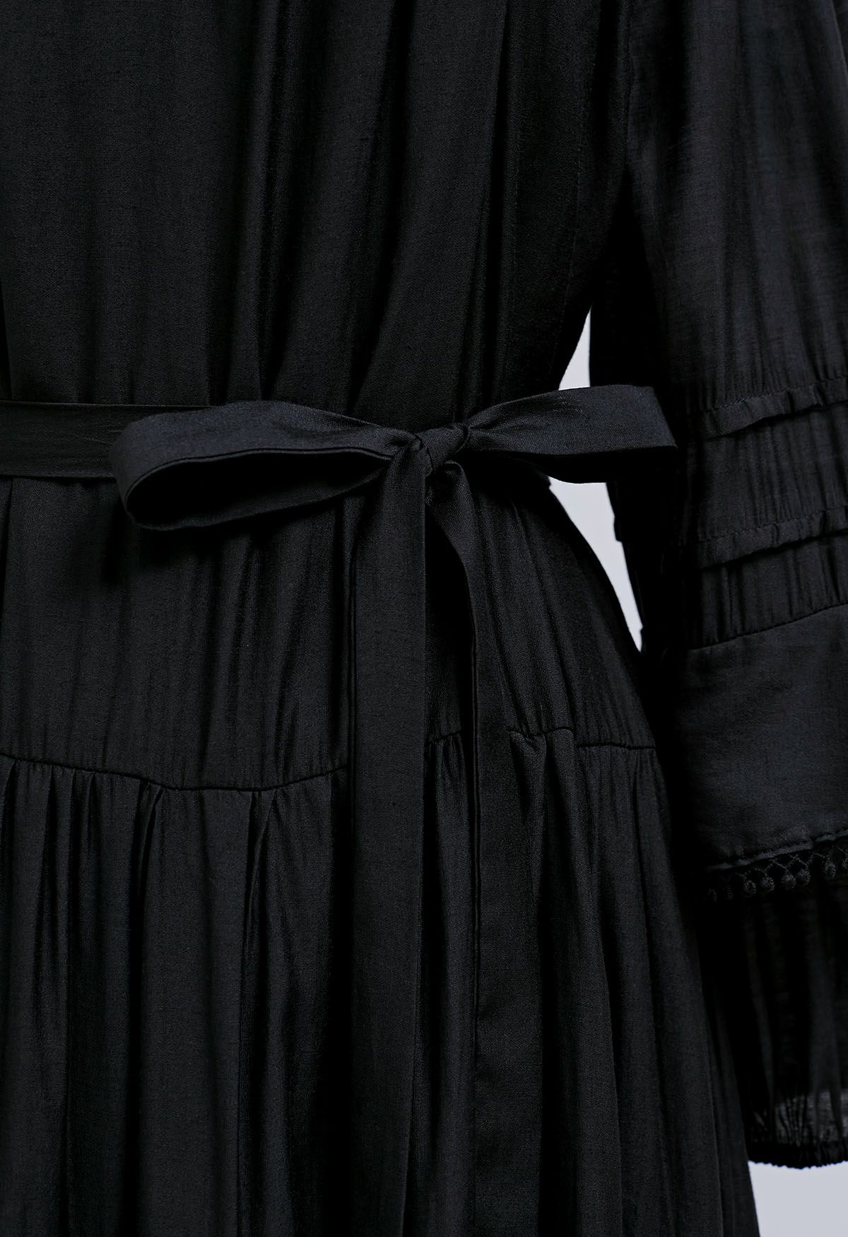 فستان قصير بأكمام متدرجة وتفاصيل هامشية باللون الأسود