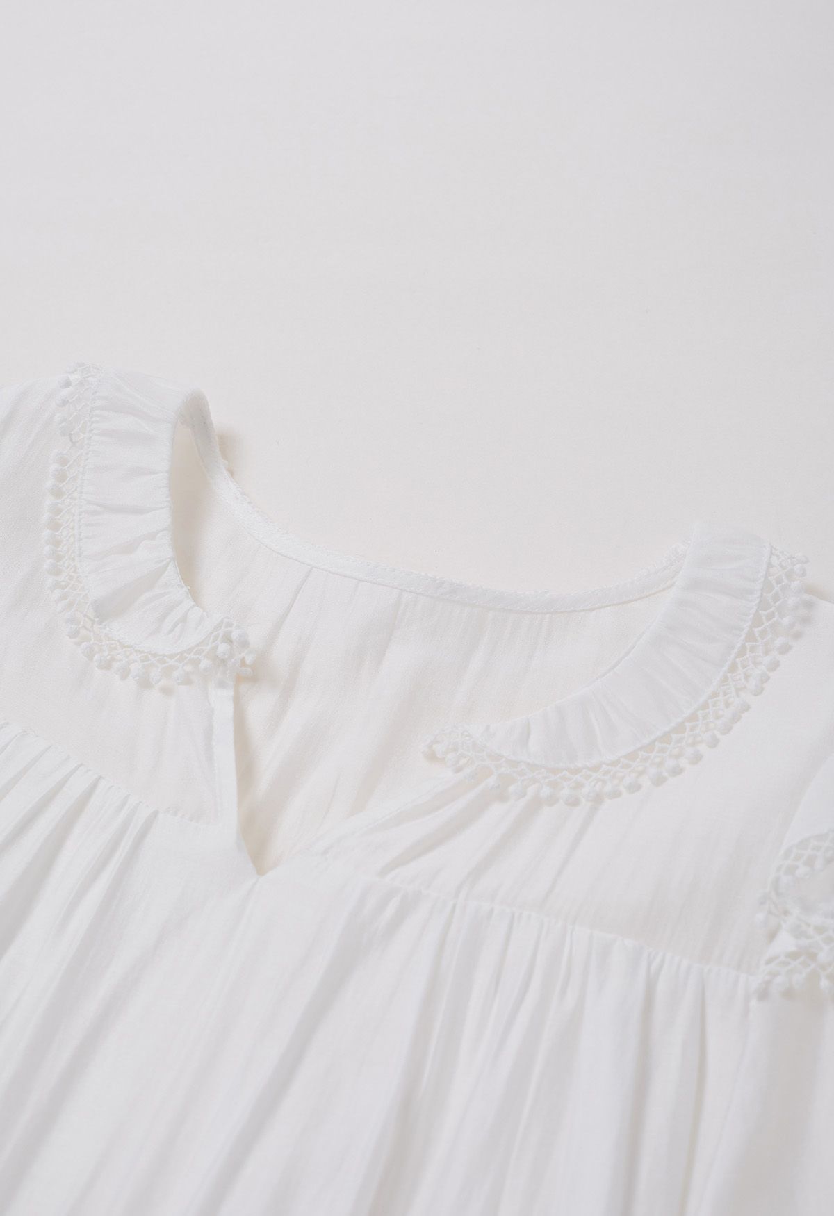 فستان قصير بأكمام متدرجة وتفاصيل هامشية باللون الأبيض